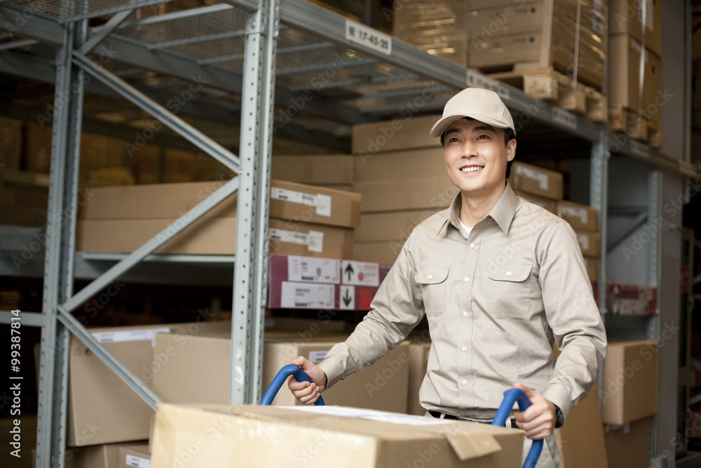 Male Chinese warehouse worker pushing boxes Male Chinese warehouse worker pushing boxes