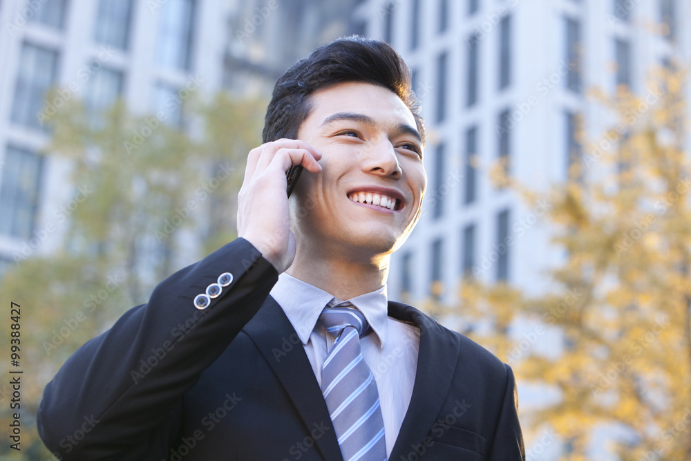 Businessman outside buildings on his mobile phone Businessman outside buildings on his mobile phone