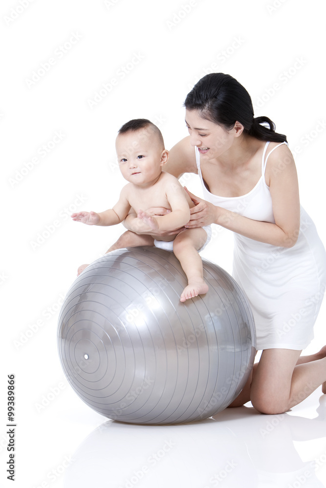 Young mother helping baby sitting on fitness ball Young mother helping baby sitting on fitness ball