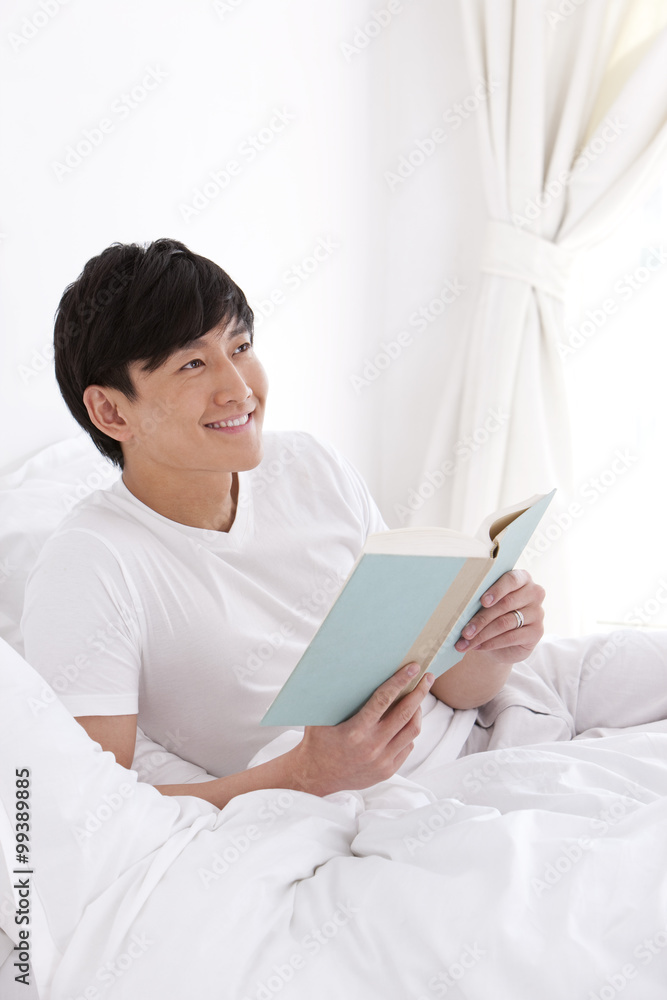 Young man reading a book in bed Young man reading a book in bed