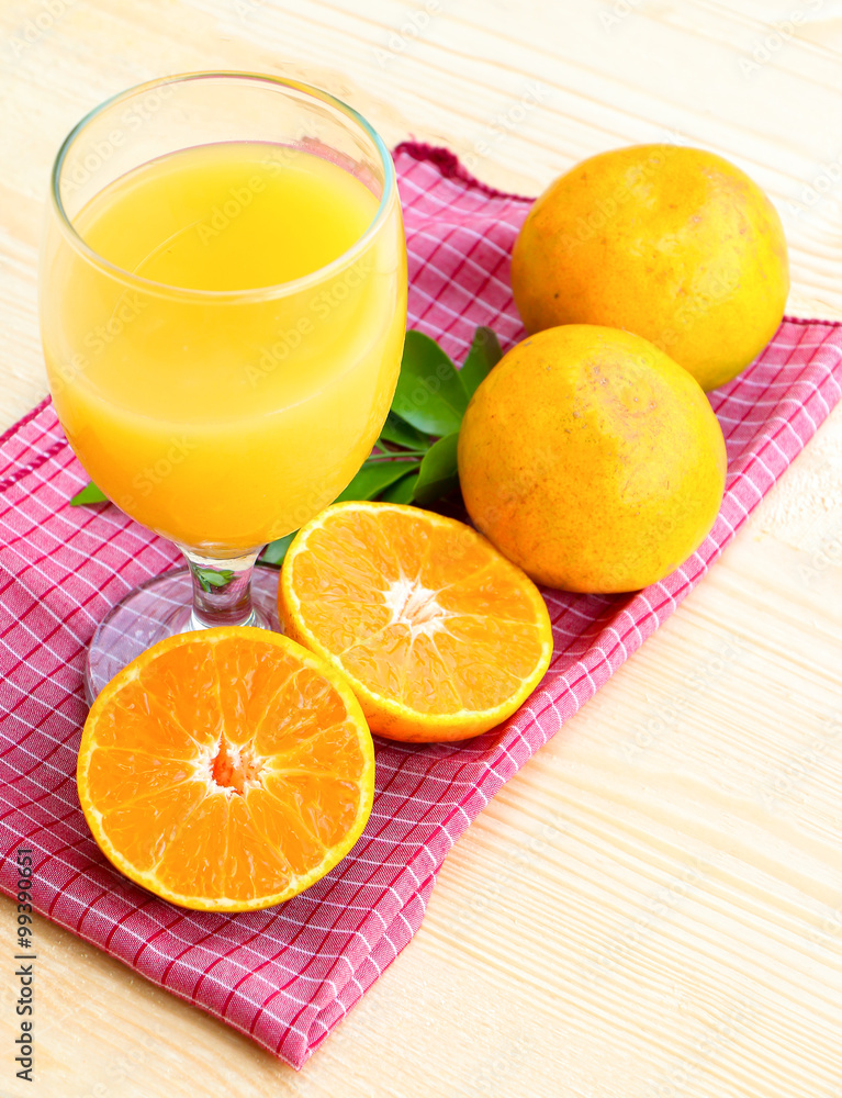 Glass of orange juice with orange slice on soft wooden background Glass of orange juice with orange slice on soft wooden background