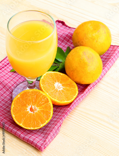Glass of orange juice with orange slice on soft wooden background