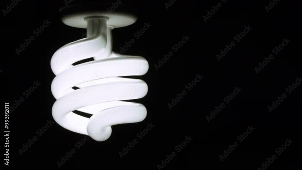 Hand installs a compact fluorescent light bulb into a ceiling fixture. Light comes on as bulb is screwed in. Locked off big close up. Hand installs a compact fluorescent light bulb into a ceiling fixture. Light comes on as bulb is screwed in. Locked off big close up.