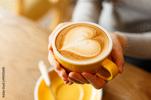 Foto lady's hands holding cup with sth heart-shaped