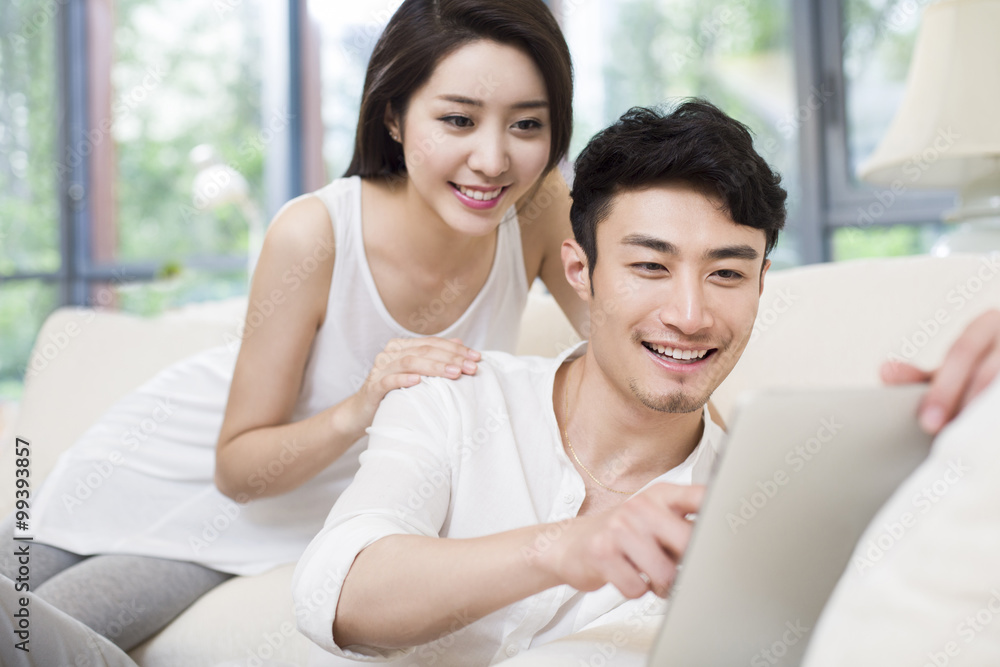 Cheerful young couple using digital tablet in living room Cheerful young couple using digital tablet in living room