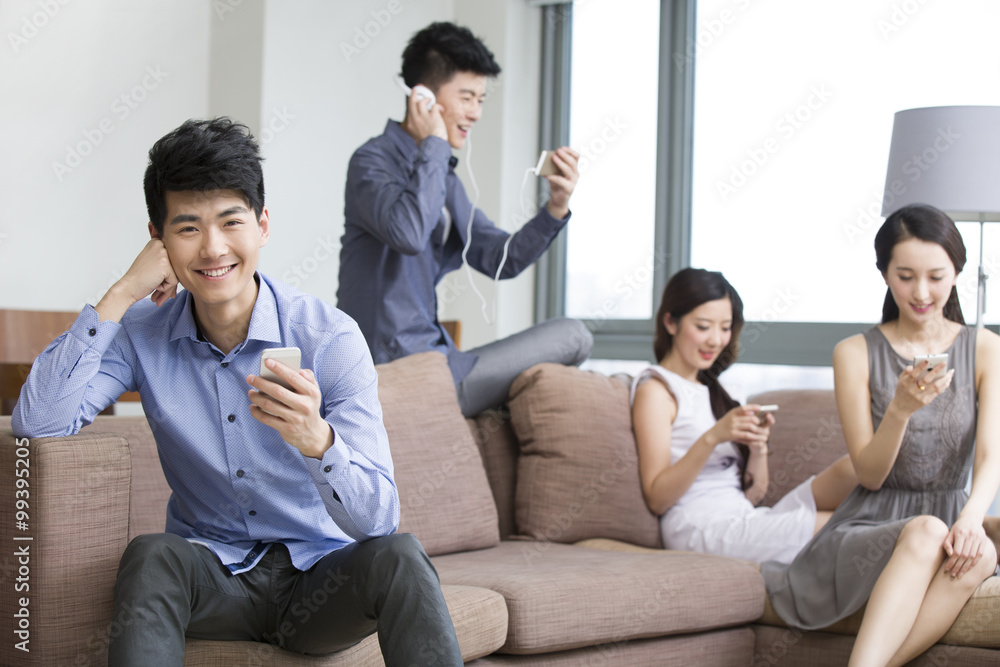 Young friends sitting on the sofa with smart phones Young friends sitting on the sofa with smart phones