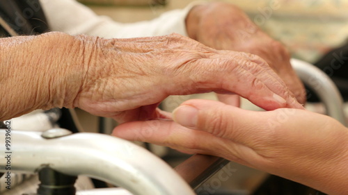 hands of a young woman petting hands of an old woman on a crutch photo