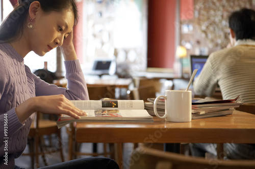 Fototapeta Naklejka Na Ścianę i Meble -  Young Woman Sitting In Cafe With Books