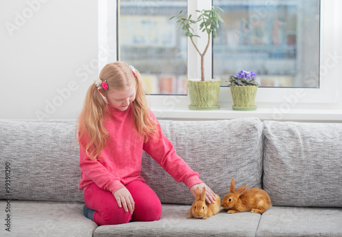 smiling girl with two rabbits indoor