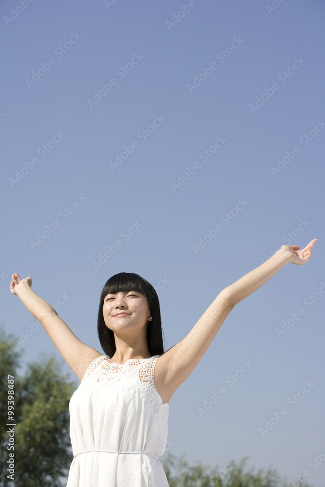 Young woman standing outdoors, arms out-stretched Young woman standing outdoors, arms out-stretched