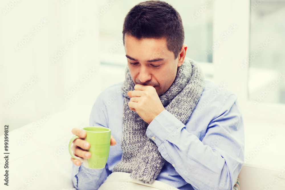 ill man with flu drinking tea and coughing at home