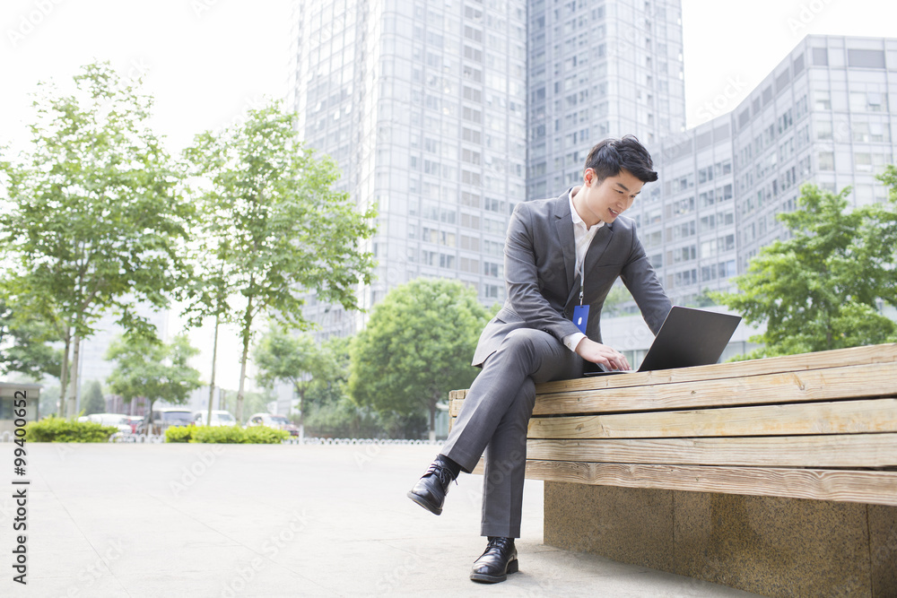 Young businessman working with laptop outdoors