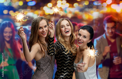 happy young women with sparklers at night club