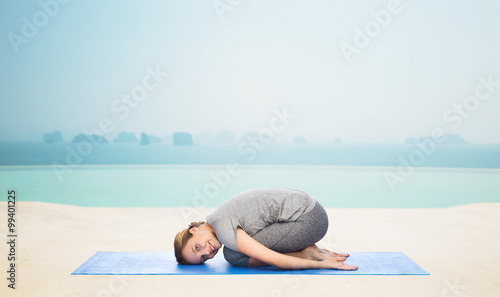 happy woman making yoga in child pose on mat