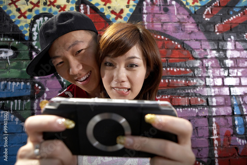 Cuadro en lienzo Teenage Boy And Girl Playing On A Game Console In Front Of A Wall Of Graffiti