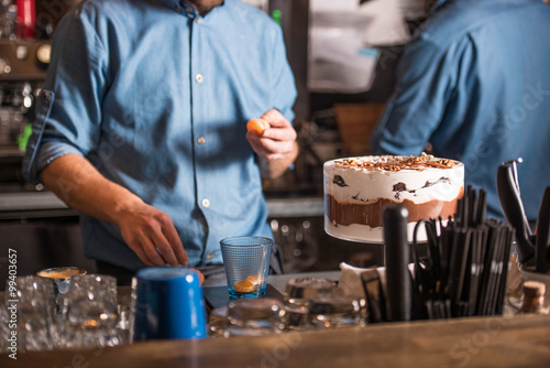 Two people standing behind the bar and prepare desserts