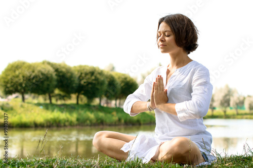 Woman meditating in sukhasana pose at the river-bank photo