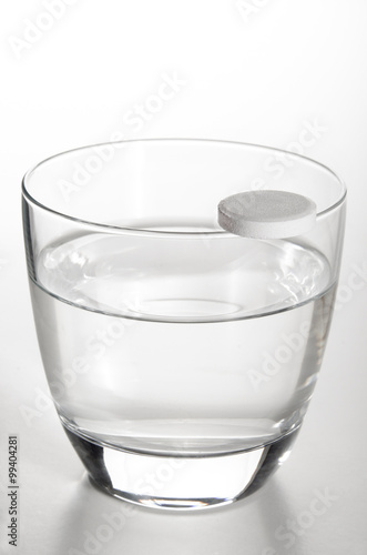 glass filled with water and a vitamin pill