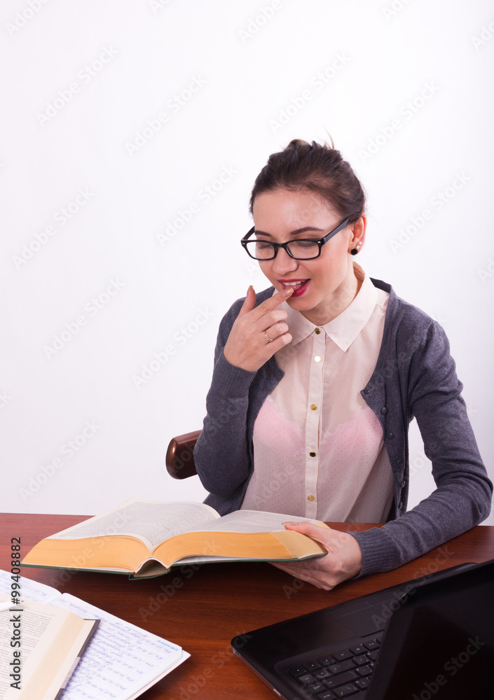 Young beautiful female teacher sitting at a table and reads the book Young beautiful female teacher sitting at a table and reads the book