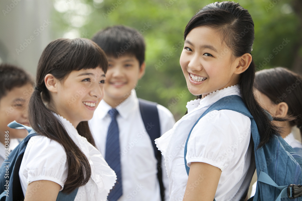 Happy schoolgirl in uniform with her friends outdoors Happy schoolgirl in uniform with her friends outdoors