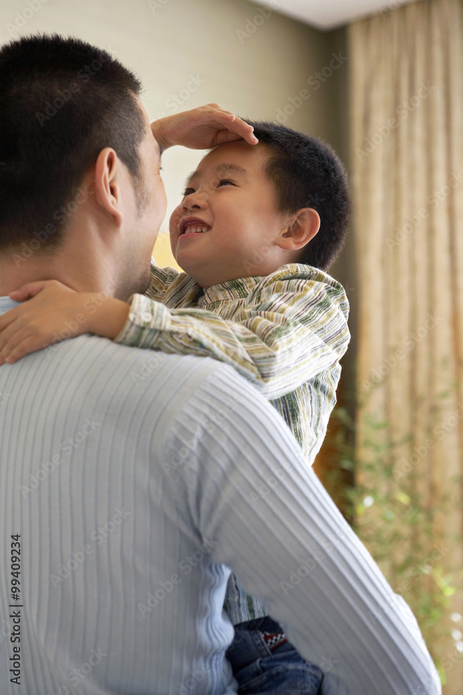 Fototapeta premium Boy Measuring His Height Against His Father