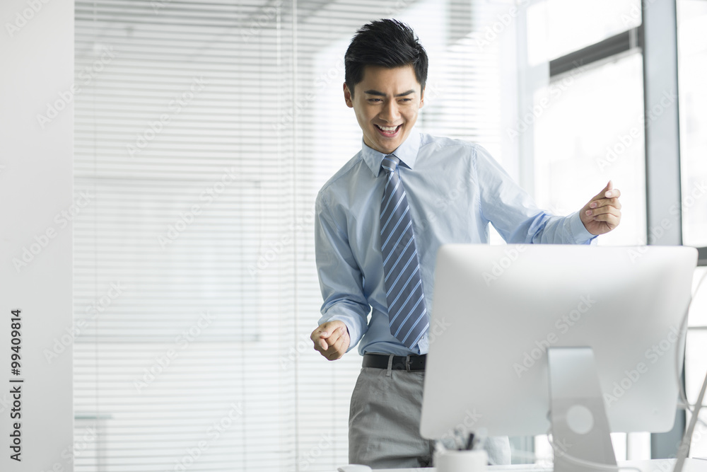 Cheerful young businessman using computer in office Cheerful young businessman using computer in office