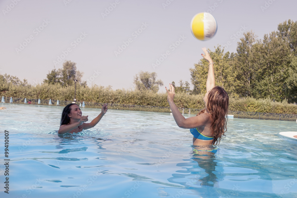 happy couple of girl relaxing in the pool playing with a ball