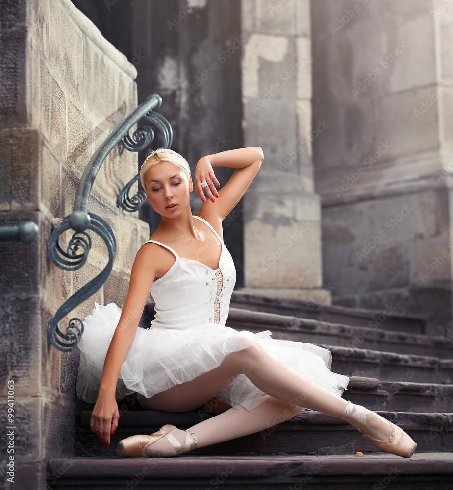Fototapeta premium Elegant and feminine. Portrait of an attractive ballerina posing sensually on the stairs of an old castle