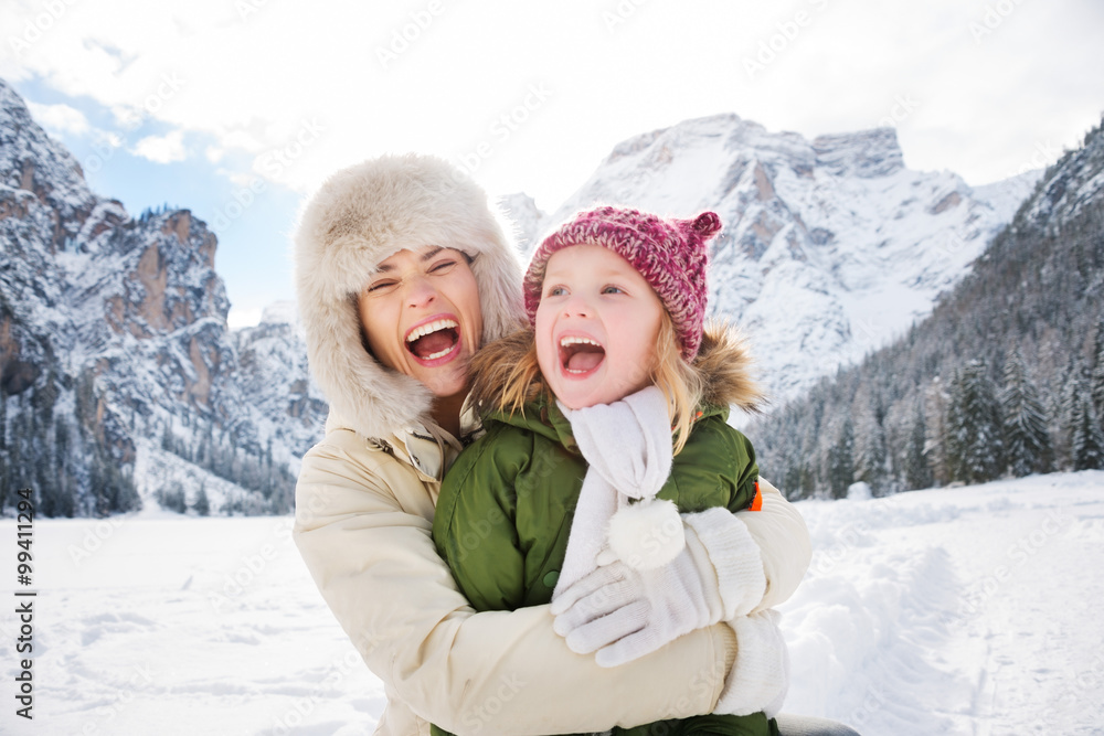 Mother and child hugging outdoors in front of snowy mountains