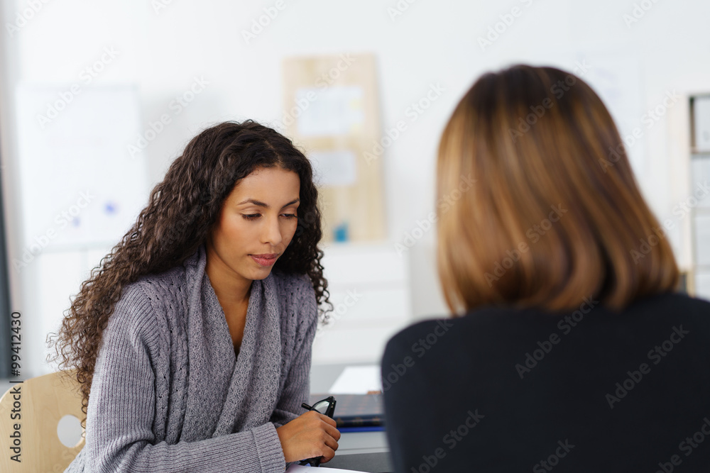 zwei frauen sitzten sich im büro gegenüber und unterhalten sich zwei frauen sitzten sich im büro gegenüber und unterhalten sich