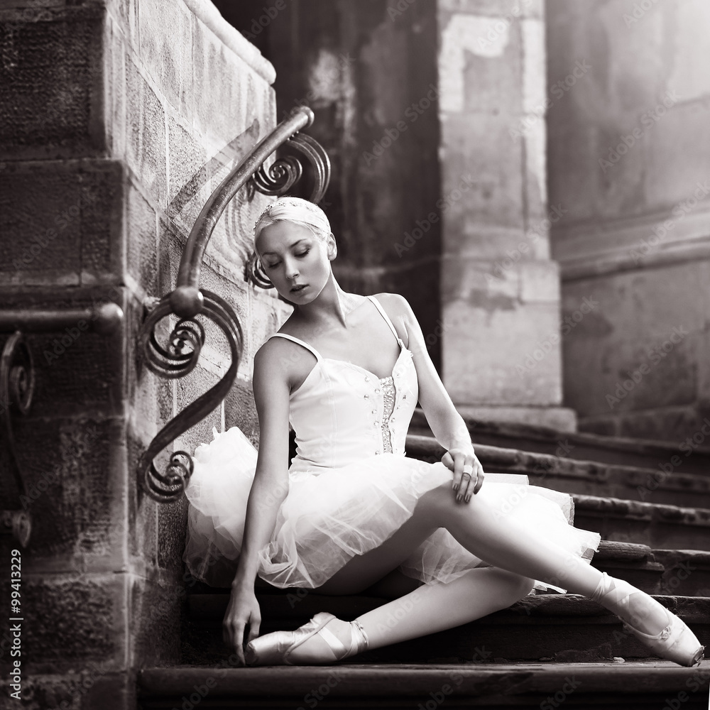 Fototapeta premium Graceful beauty. Monochrome shot of a young ballerina posing on stone stairs