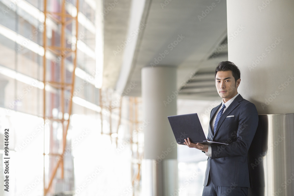 Fototapeta premium Young businessman using laptop in airport