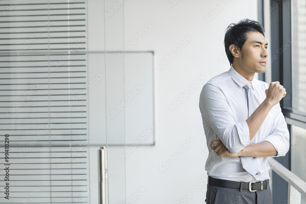 Young businessman looking through window Young businessman looking through window