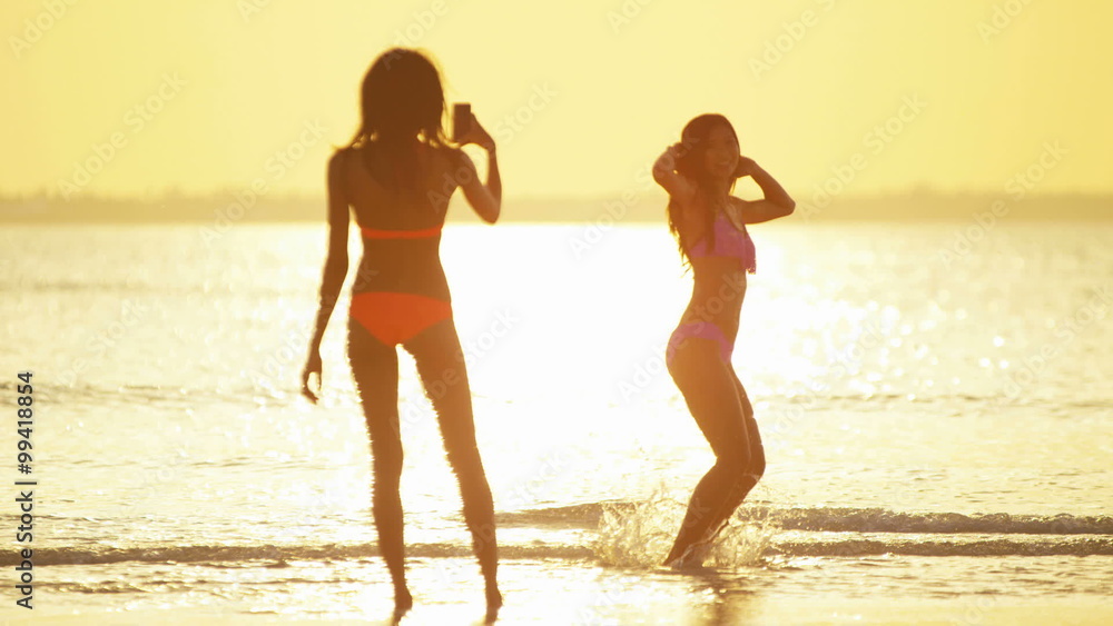 Barefoot multi ethnic female in bikini taking selfie on beach Barefoot multi ethnic female in bikini taking selfie on beach