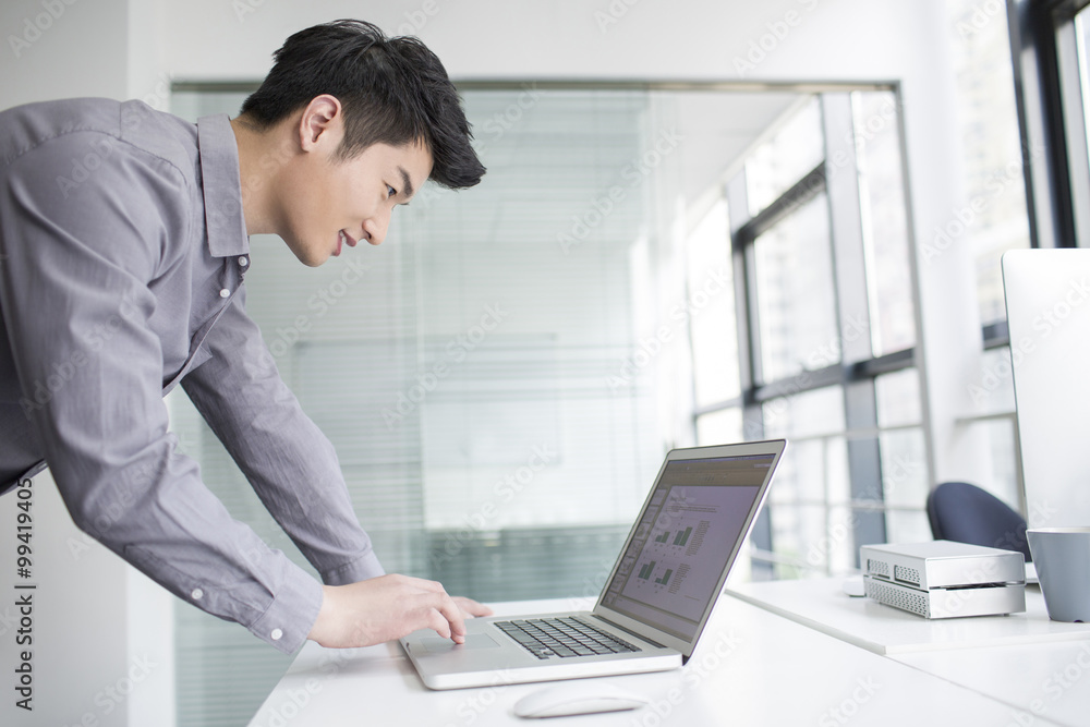 Young businessman using laptop in office