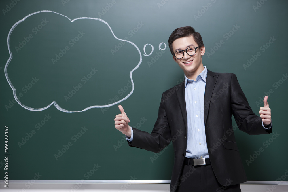 Humorous male teacher doing thumbs up in classroom Humorous male teacher doing thumbs up in classroom