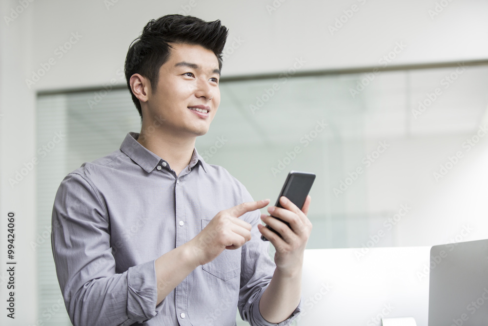 Young businessman using smart phone in office Young businessman using smart phone in office