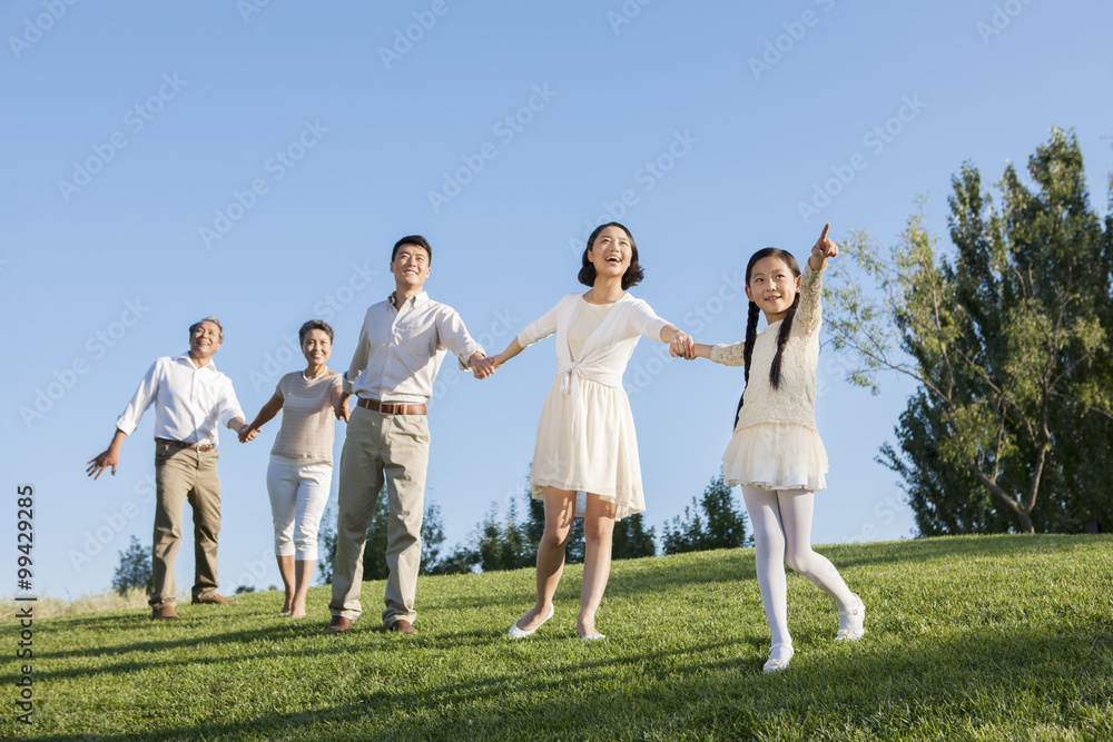 Happy family holding hands looking at view in a park Happy family holding hands looking at view in a park