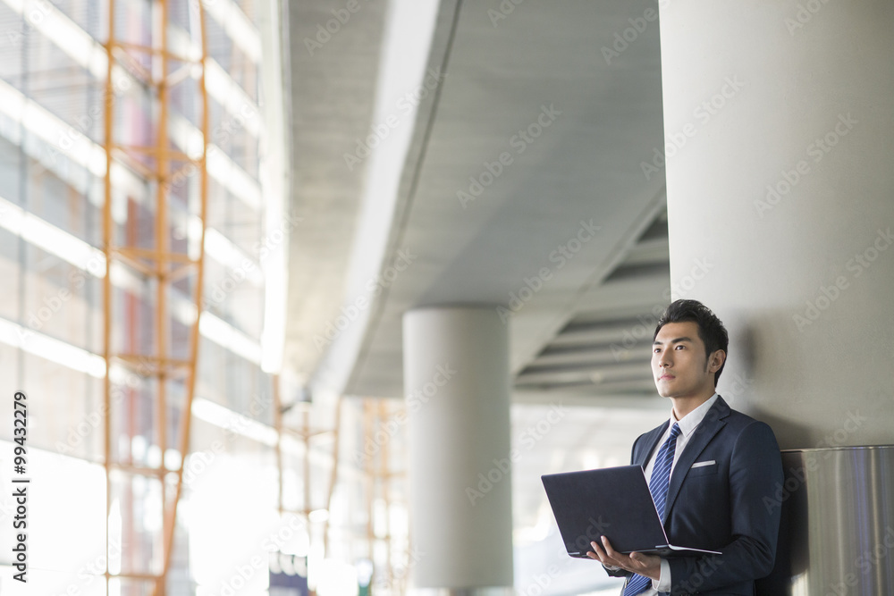 Fototapeta premium Young businessman using laptop in airport