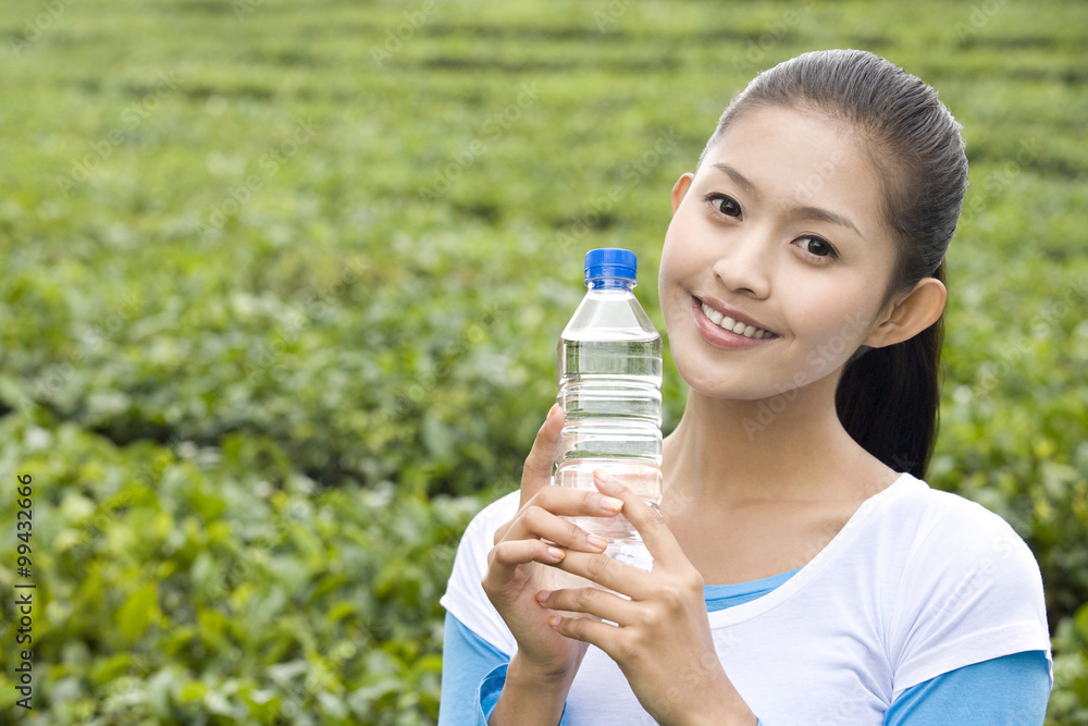 Young Woman in Tea Field with a Bottle of Water Young Woman in Tea Field with a Bottle of Water