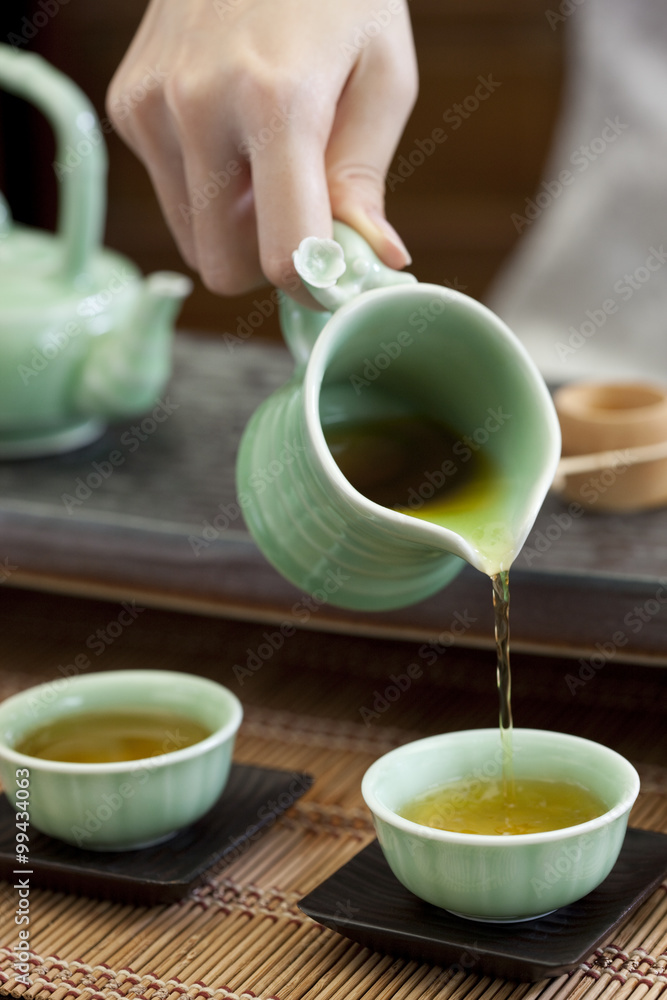 Female hand pouring tea into tea cups
