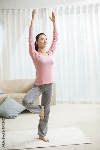 Fototapeta Naklejka Na Ścianę i Meble -  Young woman practicing yoga in living room