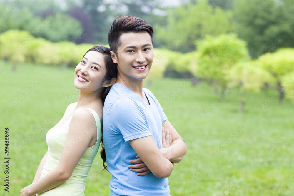 Sweet young couple in park, back to back