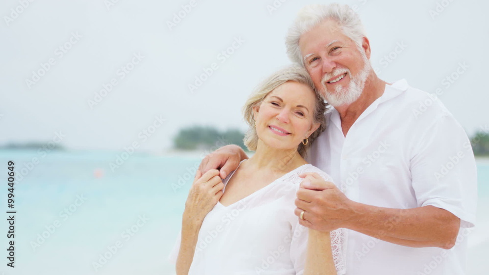 Loving senior Caucasian couple in white clothes on a beach Loving senior Caucasian couple in white clothes on a beach