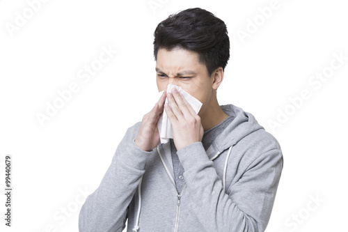 Young man blowing nose