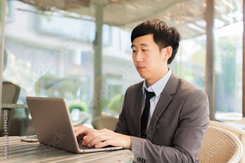 Young Asian businessman working with his laptop in outdoor scene