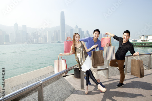 Excited young adults with shopping bags in Victoria Harbor, Hong Kong © Blue Jean Images