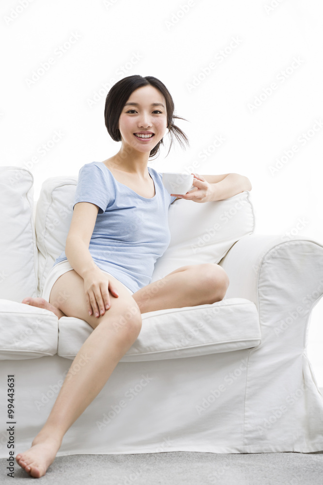 Young woman drinking coffee on sofa Young woman drinking coffee on sofa