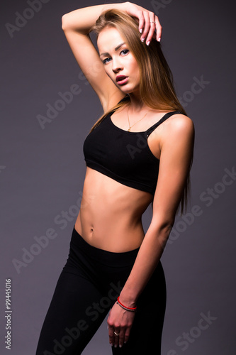 Young woman doing gymnastic exercise on grey isolated background. Tenderness, grace, melody and plastic of gymnastic girl. 