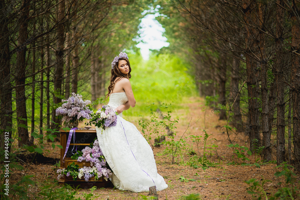 the bride poses in the wood near a case with a lilac
the bride poses in the wood near a case with a lilac